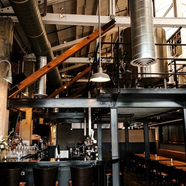 Industrial-chic interior of The Noble Fox restaurant with exposed brick, a bar, and brewing equipment.
