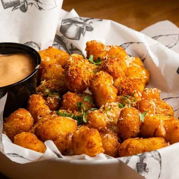 Golden fried tater tots with parmesan and parsley, served with a side of dipping sauce.